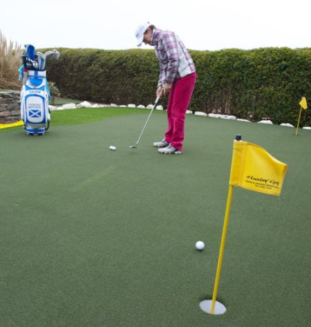 Image caption: Catriona Matthew MBE practises putting on her new 375 square feet (114 square metre) Huxley Premier Putting and Chipping Green