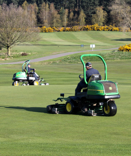 Two of the John Deere 2500E electric hybrid greens mowers at work on this traditional heathland course, which features heather, fern, gorse and pine in abundance.