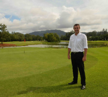 Laguna Phuket's director of golf, Paul Wilson, beside the 8th green with Phuket's iconic mountains in the background