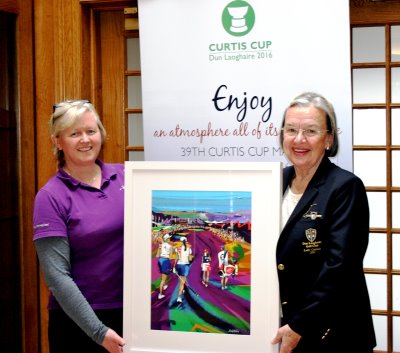 Lucy (left) presenting the original artwork to Liz Jordan, Lady Captain of Dun Laoghaire G.C