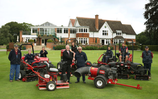 Course manager Sid Arrowsmith shakes hands with Lely’s Robert Rees, left, in front of the club’s new Toro machines and members of the greenkeeping team