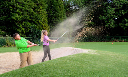 South Moor youngsters Dan Welsh and Abbi Wheatley splash out of the practice bunker on the biggest Astroturf golf practice area in Europe (photo Ian Horrocks)