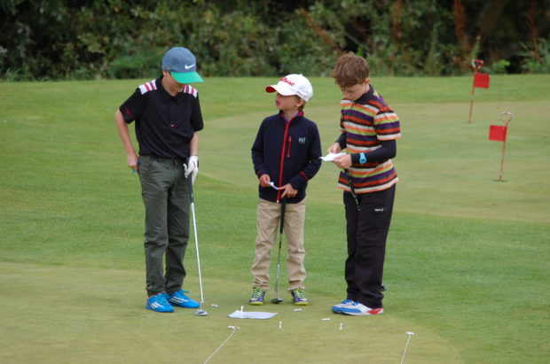 Three young players weigh up their options on the practice putting green at Houghwood Golf Club at the end of season competition for players on the under 14 coaching programme