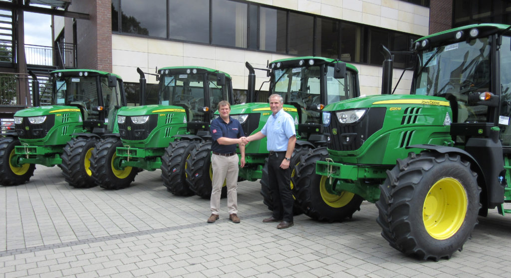 Adrian Abbott (left) of MJ Abbott Limited and Jamie Fisher of dealer R Hunt Ltd with the new John Deere 6120M tractor fleet during the handover at the Mannheim tractor factory in Germany.